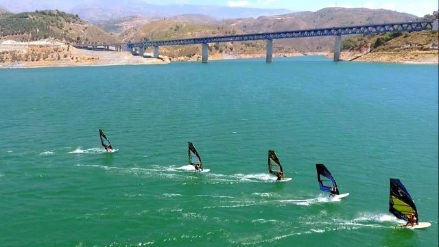 Aerial view of wingfoilers racing across the reservoir